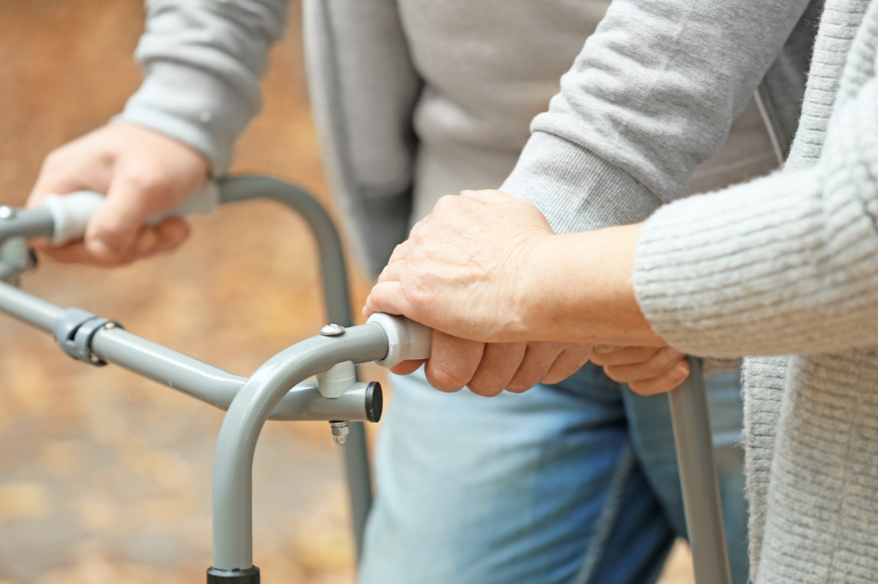 A person using a walker is helped by another person
